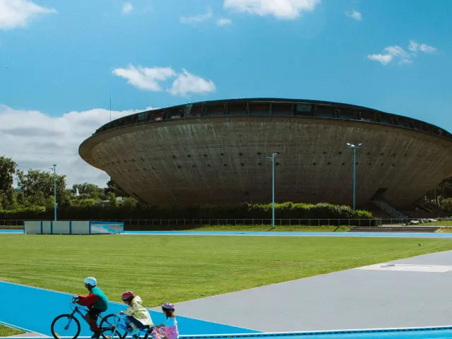 Enfants faisant du vélo sur le terrain de sport à côté de la Soucoupe